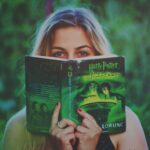 Kobieta czyta książkę o Harrym Potterze w zielonym parku