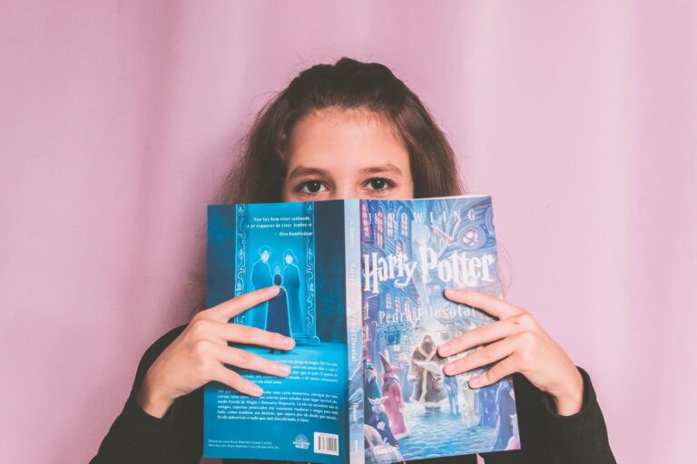 Dziewczynka z książką o Harrym Potterze na różowym tle